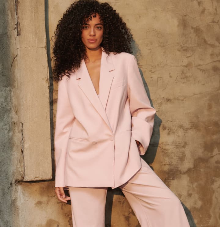  Model is wearing a pink oversized blazer and pants.
