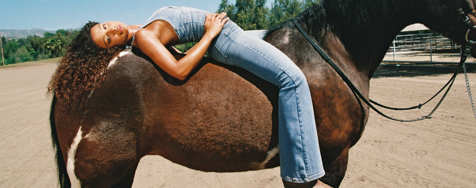Girl poses on a horse wearing a denim top and matching jeans.
