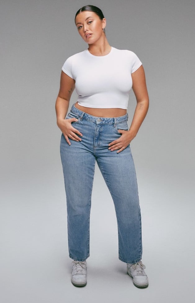 Model is wearing white crop top and blue denim.