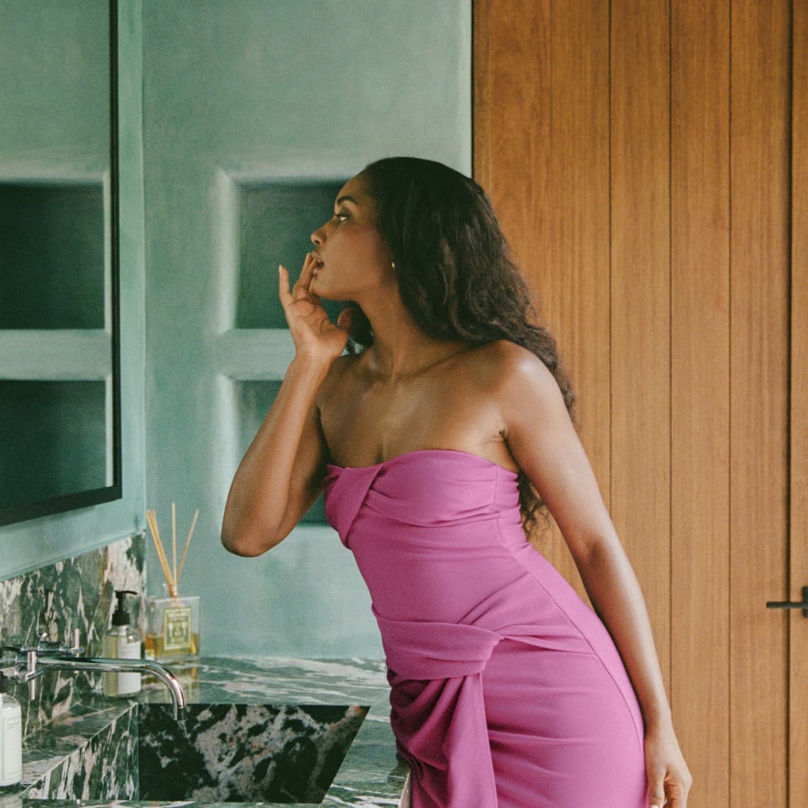 Model is wearing a pink draped mini tube dress.