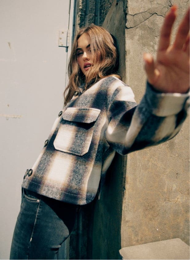 La mannequin porte un blouson écourté à carreaux.