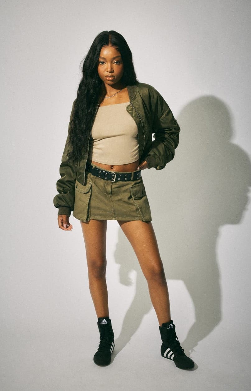 Model wears a cropped tank top, a bomber jacket, and a mini skirt.