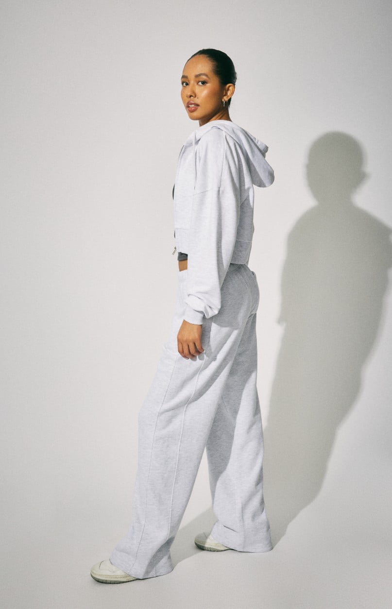 Model wears a grey hoodie and matching sweatpants.