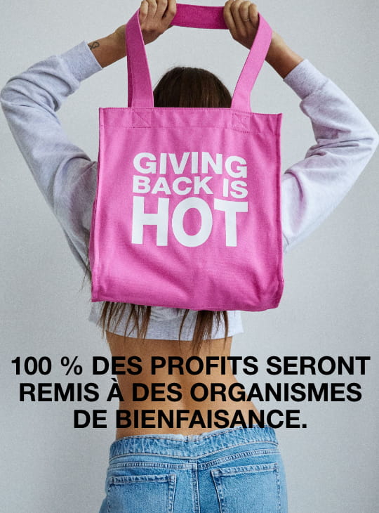 La mannequin tient un sac caritatif sur lequel il est écrit « Giving Back is Hot »
