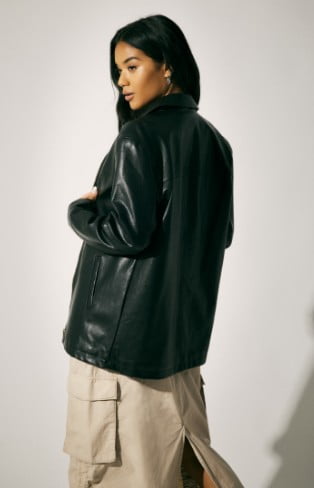 Model is wearing a faux leather jacket, black top, and a cargo skirt.