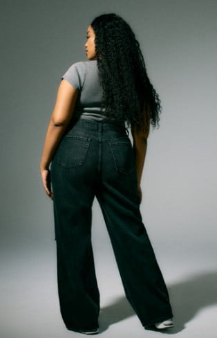 Model is wearing a grey top, and dark washed denim.