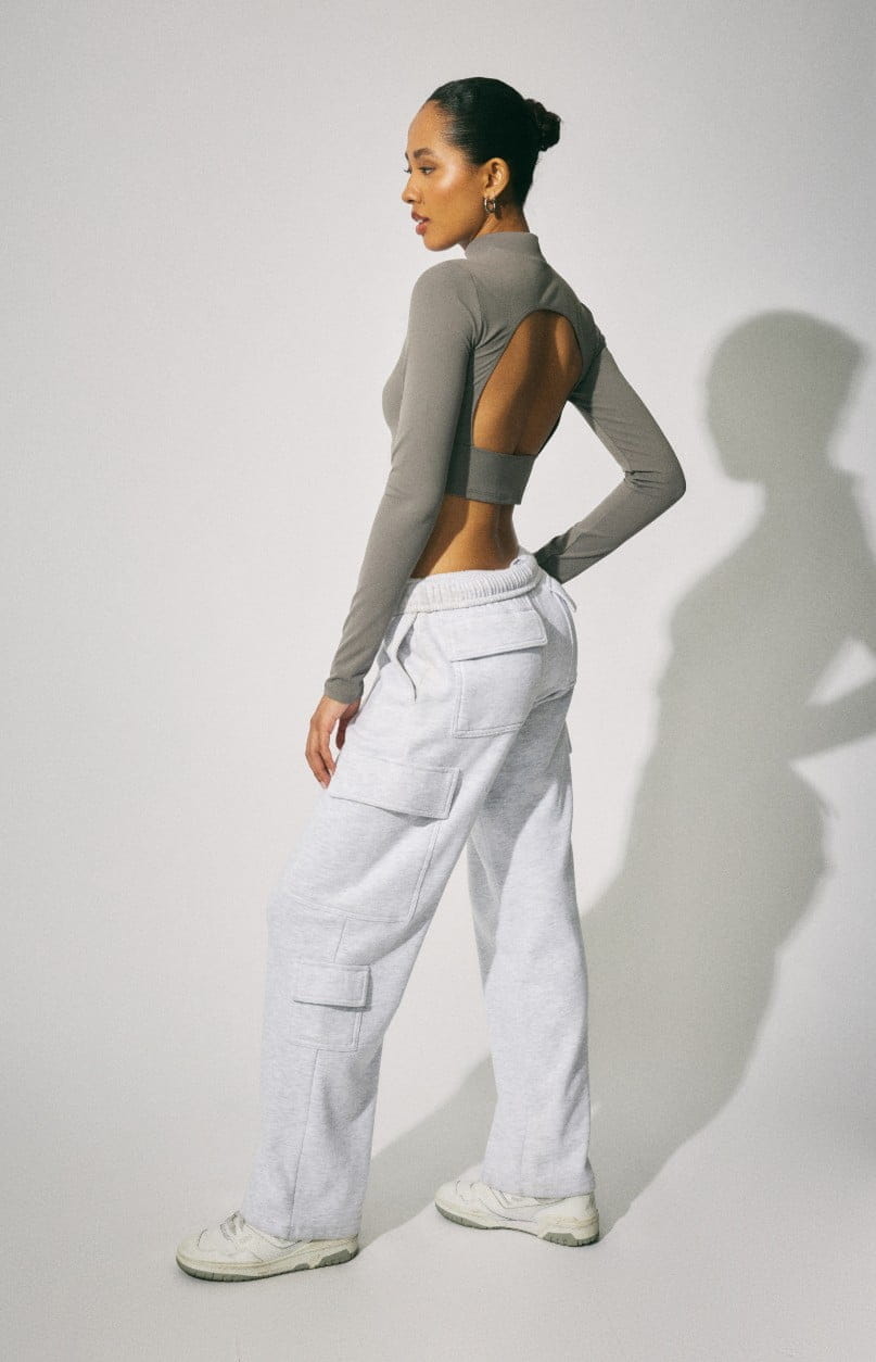 Model wears a cropped long sleeve shirt and grey joggers.