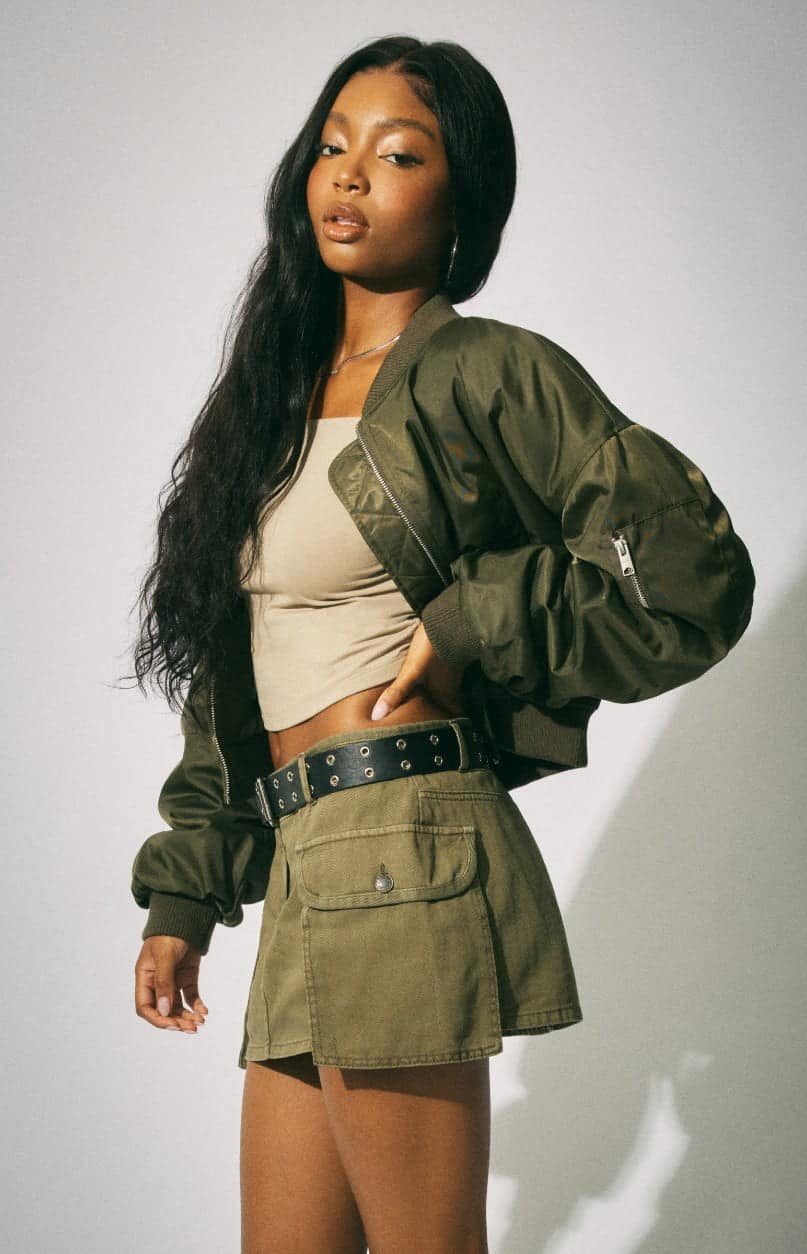 Model wears a cropped tank top, a bomber jacket, and a mini skirt.