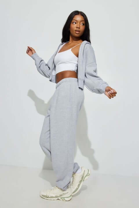 Model wears a grey sweatsuit with a white tank top and off-white sneakers.