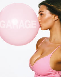 Model blows a bubble in a pink tank top.