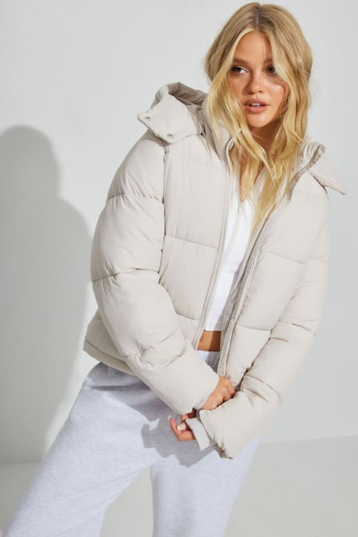 Model wears a white puffer coat on top of a white t-shirt and sweatpants.