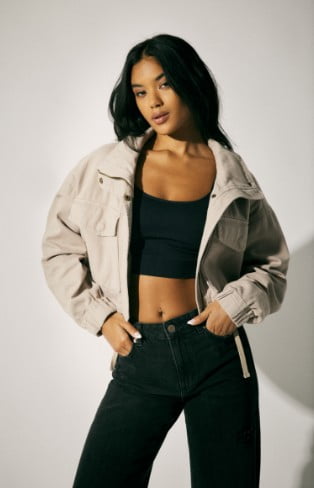 Model is wearing a cropped jacket, black crop top and bottoms.