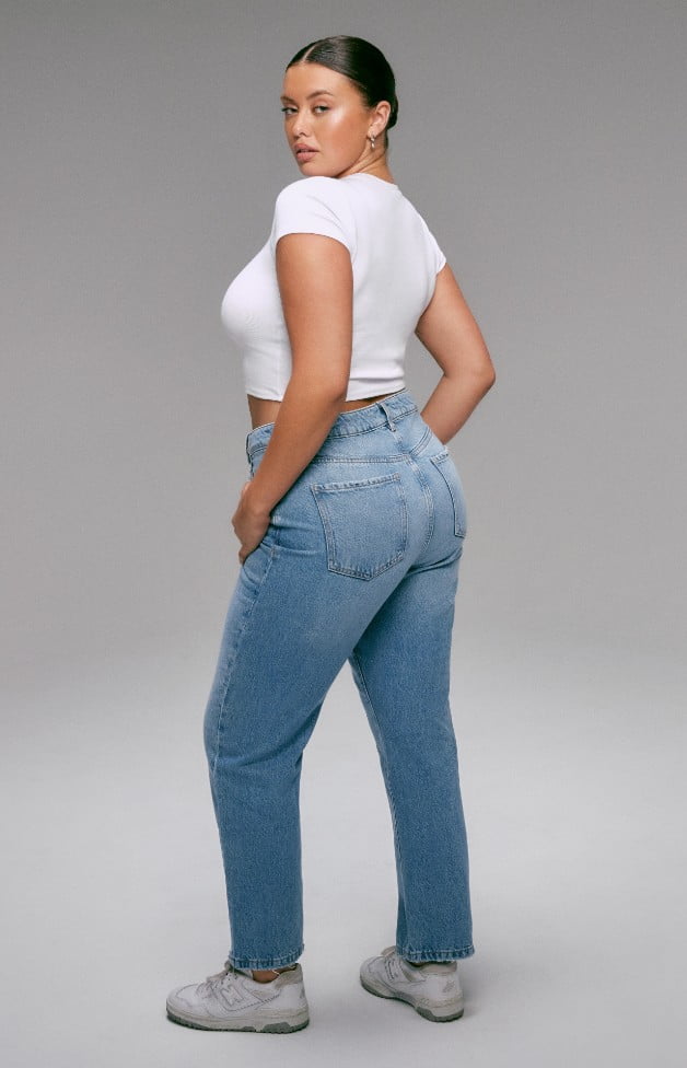 Model is wearing white crop top and blue denim.