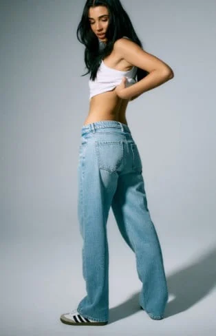 Model is wearing a white top and loose denim.
