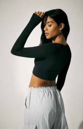 Model is wearing a black longsleeve top and parachute pants.