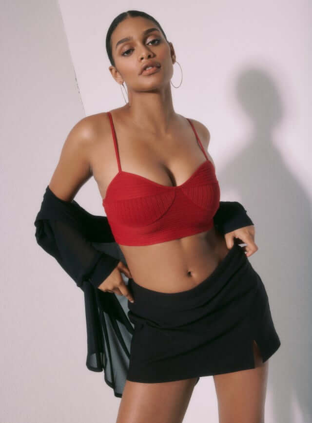 Model is wearing a red bustier, a black mini skirt and black overpiece shirt.