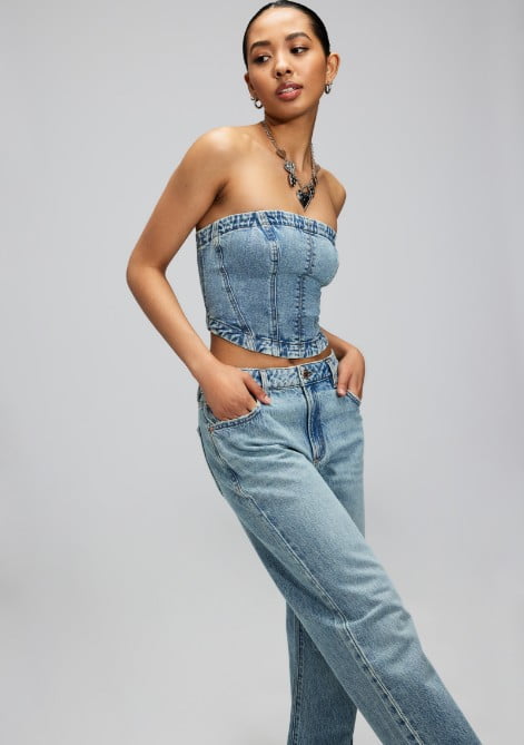 Model poses wearing a denim corset top and matching jeans.