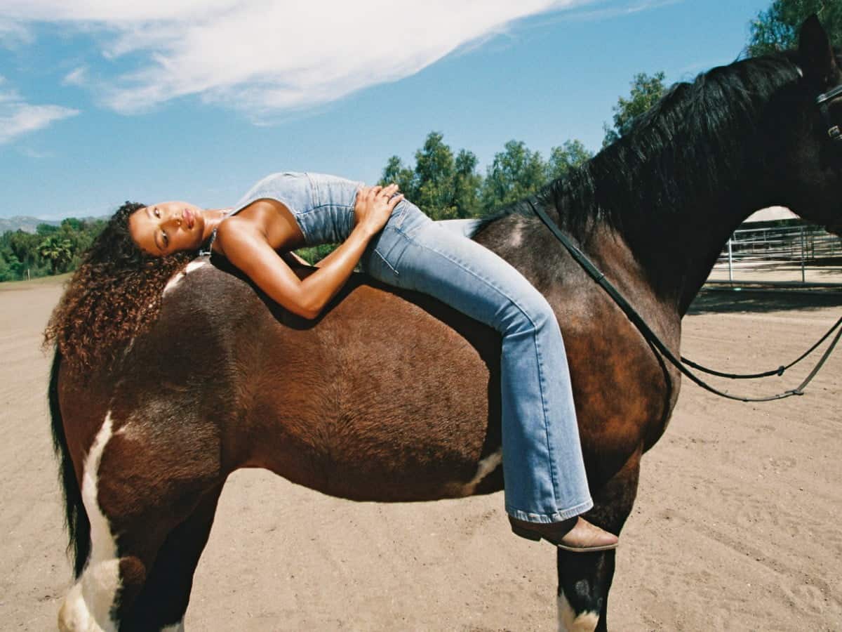 Model poses on a horse in jean set.