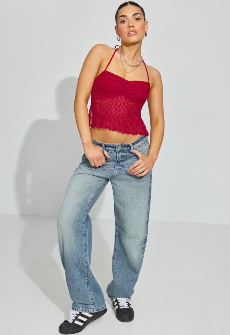 Model wears a red polka dot halter top, jeans, and sneakers.