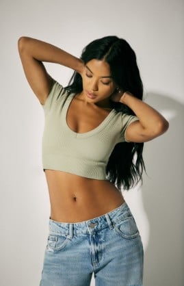 Model is wearing a green top and blue denim.