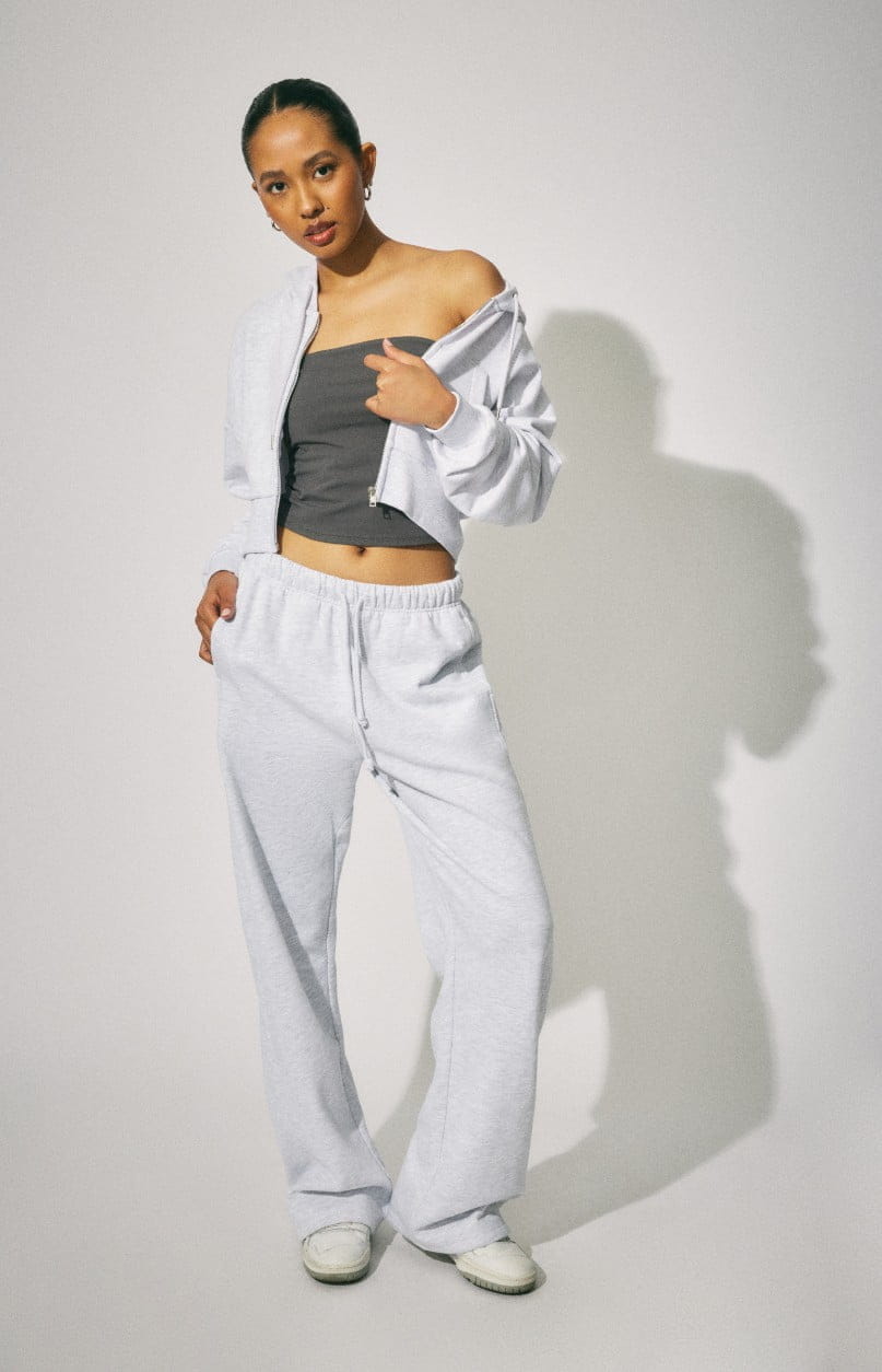Model wears a grey hoodie and matching sweatpants.