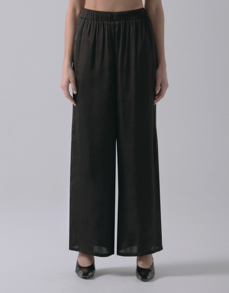 A model wears black wide leg satin pants.