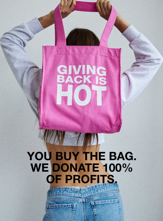 model is holding charity tote that says Giving Back is Hot