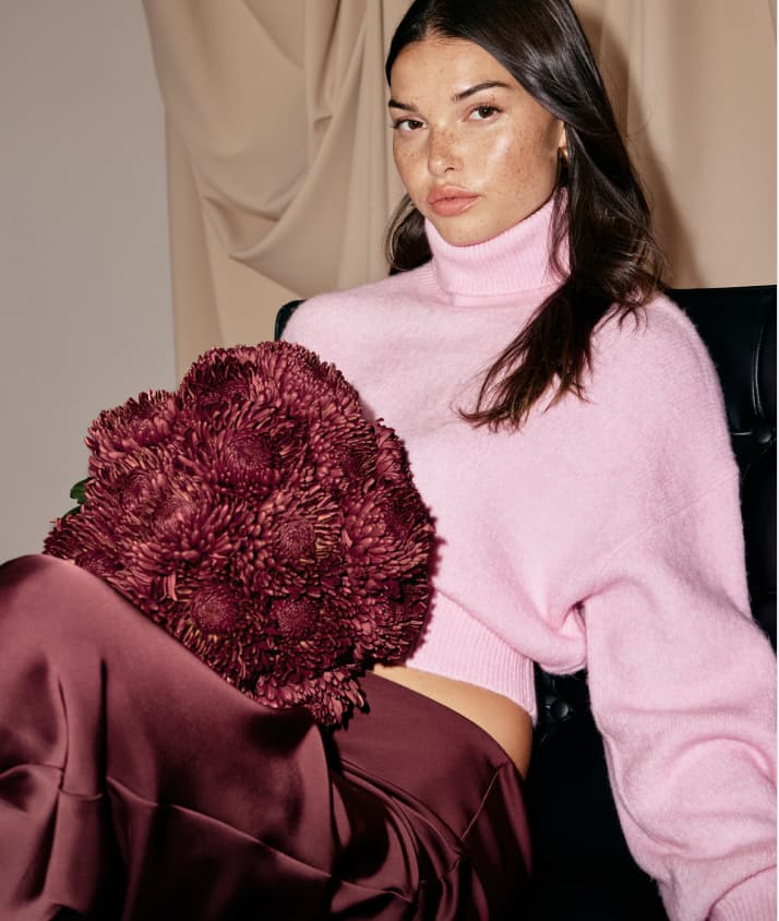Model is wearing a pink turtleneck and burgundy satin maxi skirt.