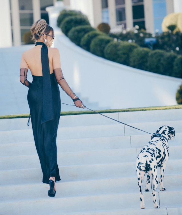 Une influenceuse porte une robe en satin noir et col licou avec une fente sur la jambe.
