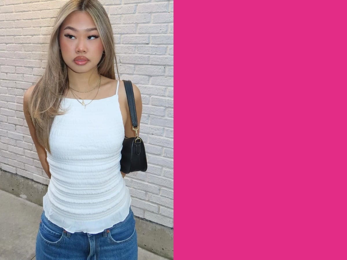 Model poses in a white top and blue denim jeans.