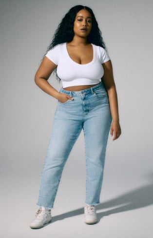 Model is wearing a white top and tapered denim.