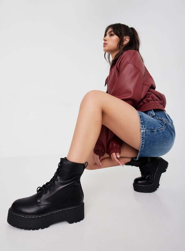 Model is wearing black platform boots by Steve Madden.