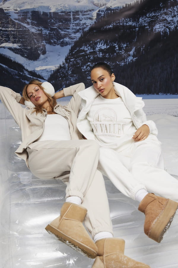 Models are wearing a beige and white sweatset with a puffer jacket on top.