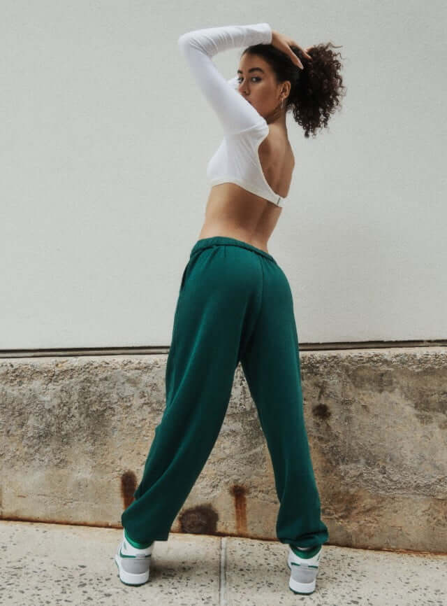 Model is wearing a white crop top and green joggers.