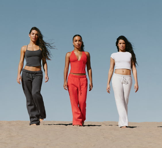 Group of models in the desert in a mix of dark grey, white, and orange outfits.