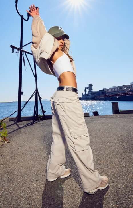 A model wears a white tank and off-white cargos.
