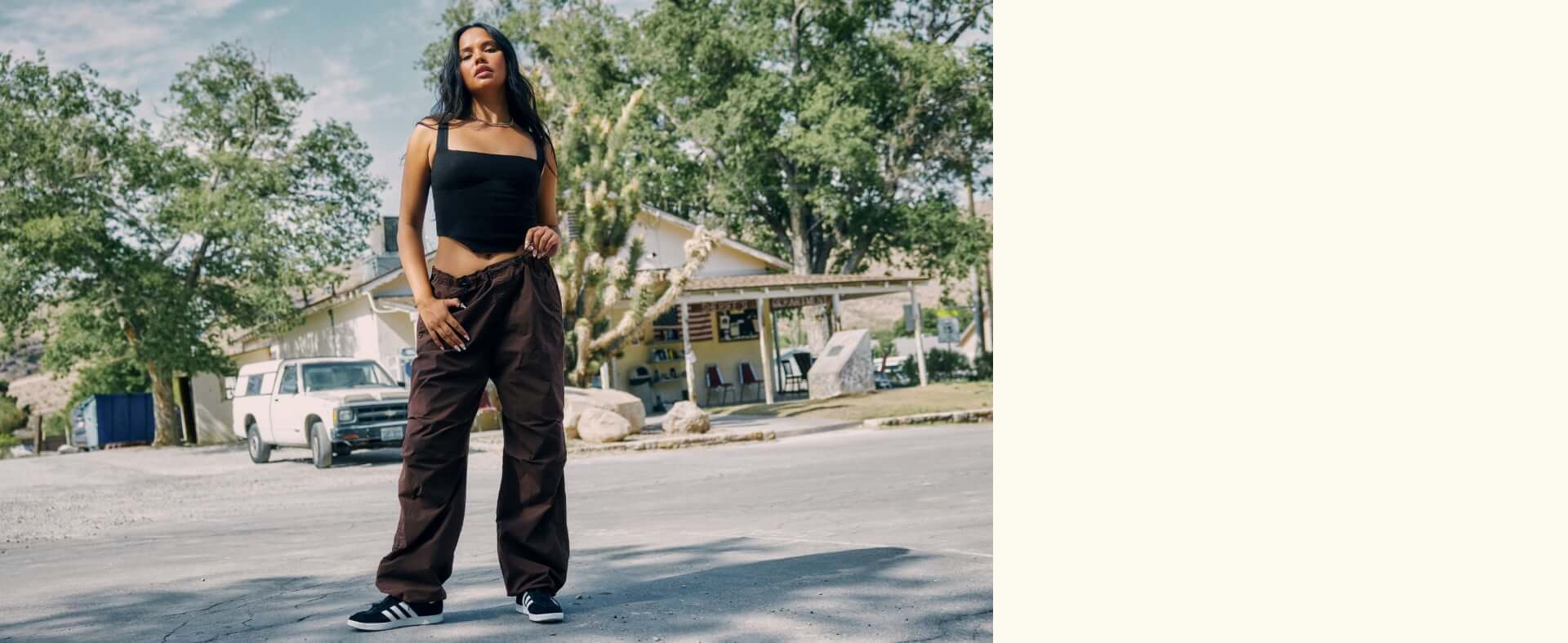 Model is wearing a black corset and brown parachute pants.