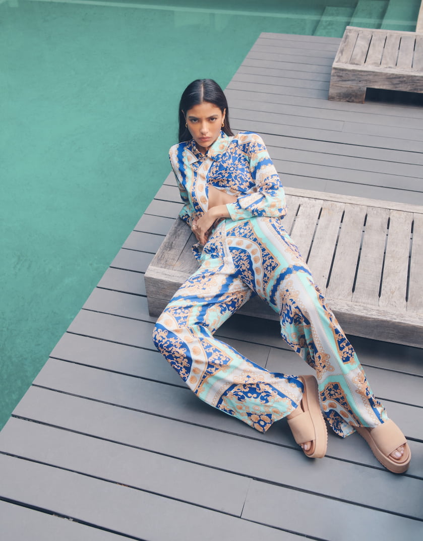 A model wears a blue and beige printed shirt and pant set.
