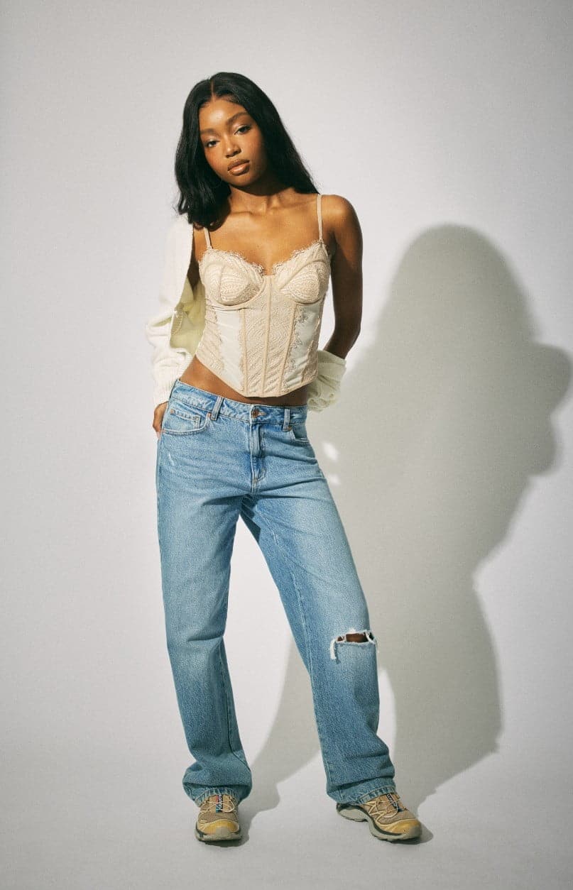 A model wears corset top, white cardigan, and ripped jeans.
