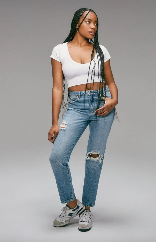 Model is wearing a white top and mom jeans