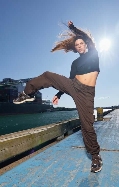 Model is wearing a cropped long sleeve shirt and brown cargos.