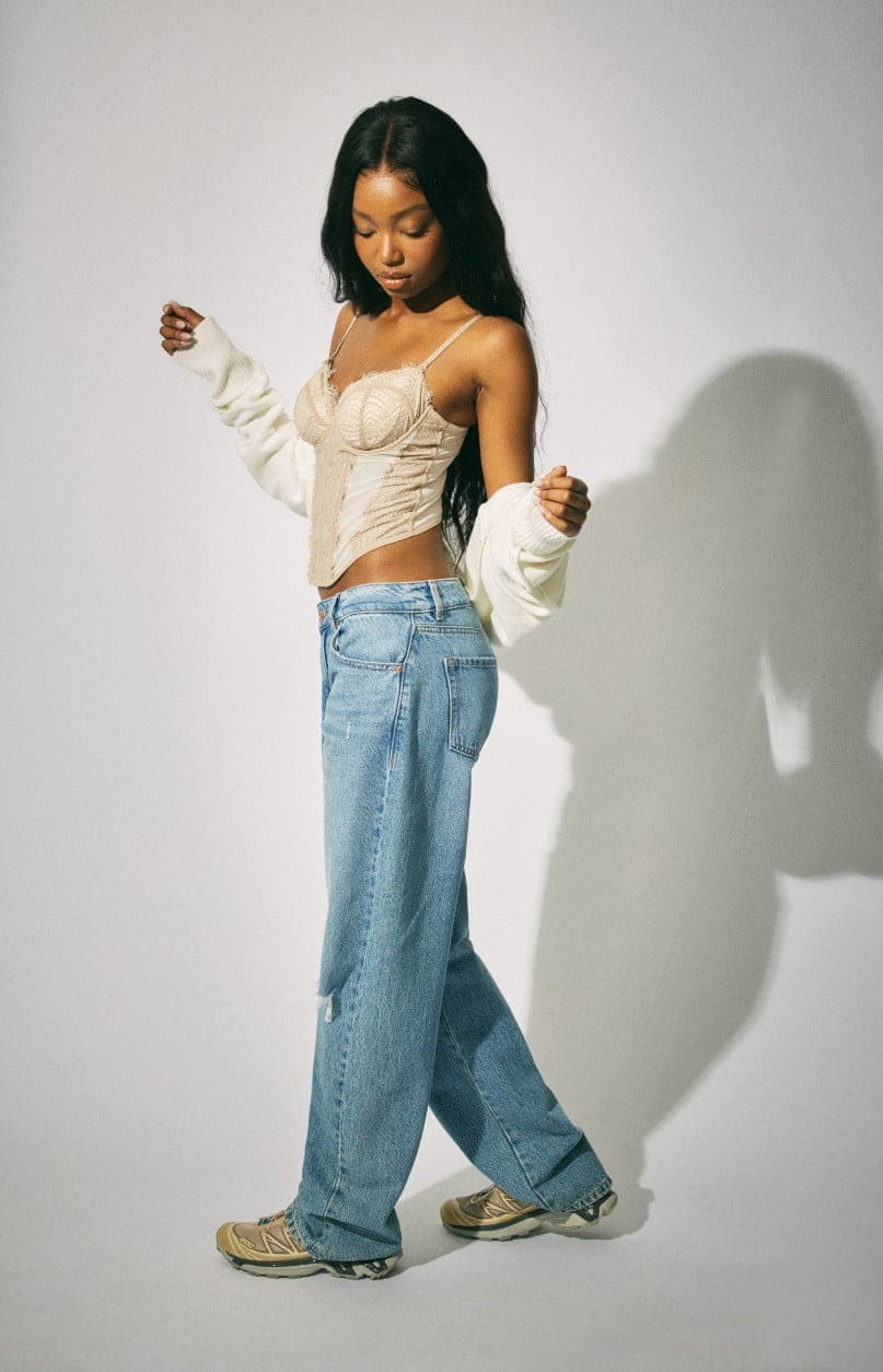 A model wears corset top, white cardigan, and ripped jeans.