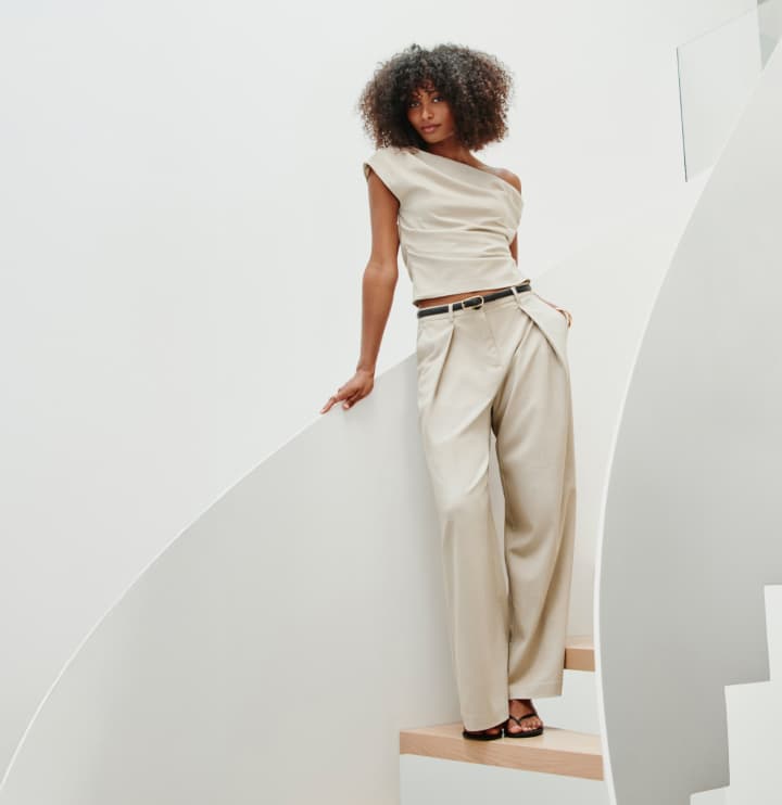 Model is wearing a beige off shoulder top and pants.