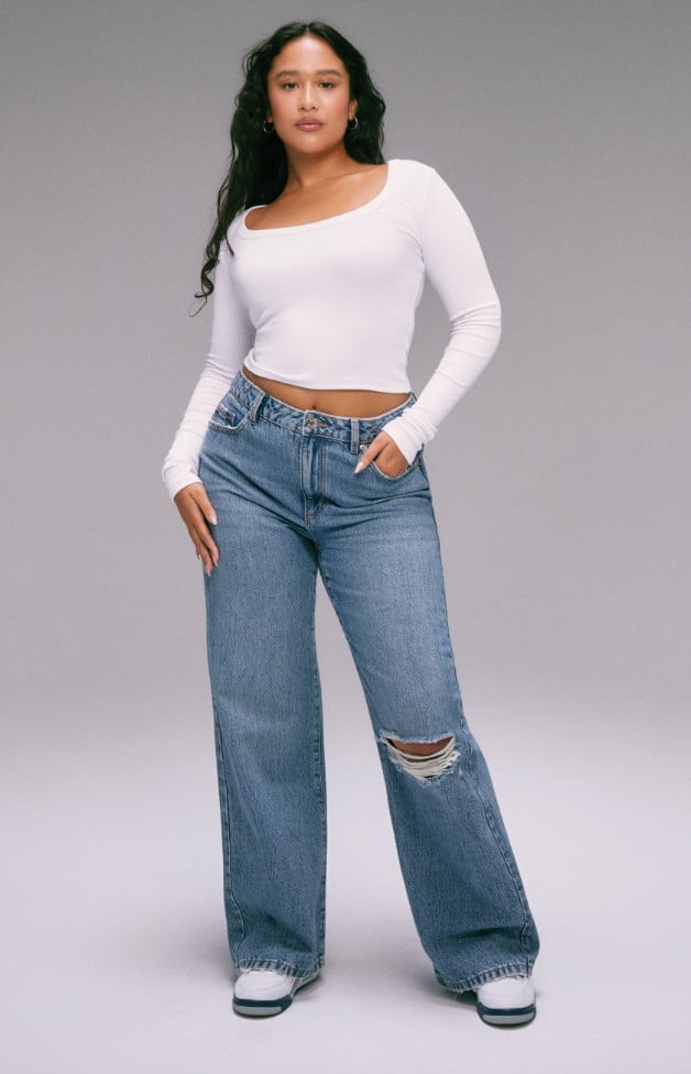 Model is wearing white long sleeve shirt with wide leg jeans.