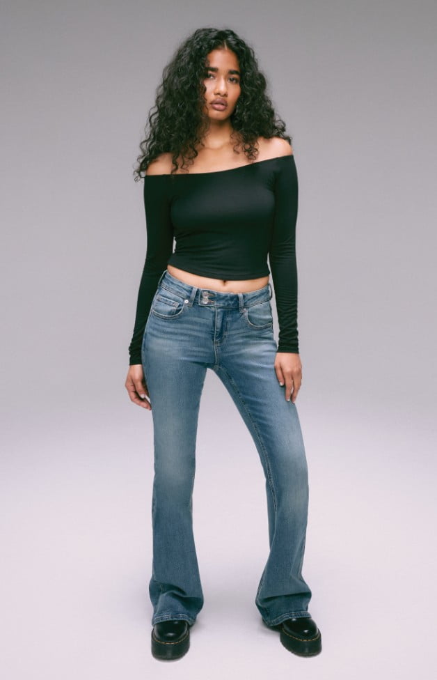 Model is wearing a white top and loose denim.