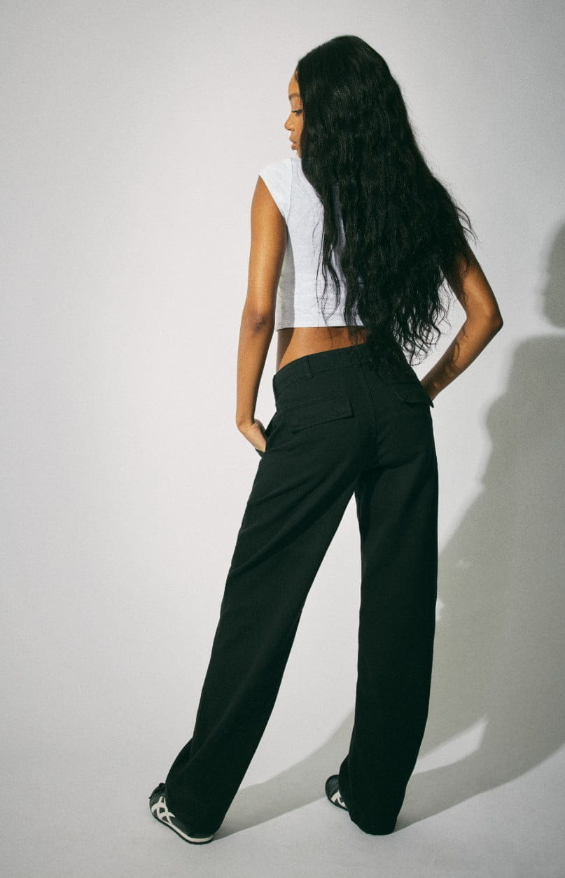 Model poses in a cropped grey tshirt and black trousers.