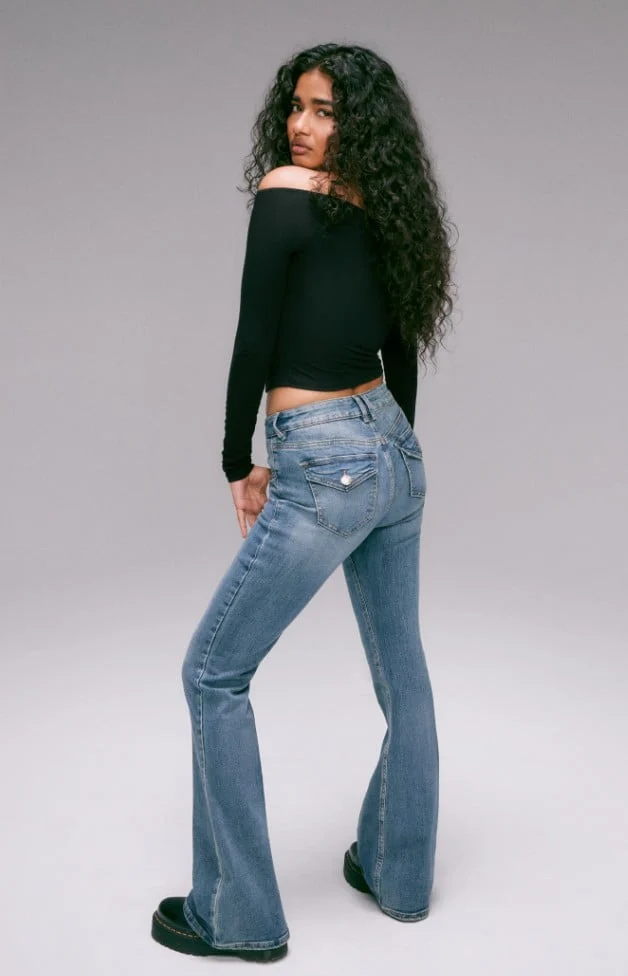 Model is wearing a white top and loose denim.