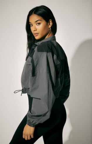 Model is wearing a cropped jacket and a black jumpsuit.