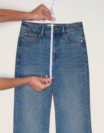 Place the measuring tape from the top of the waistband to the bottom of the crotch seam on a pair of jeans.