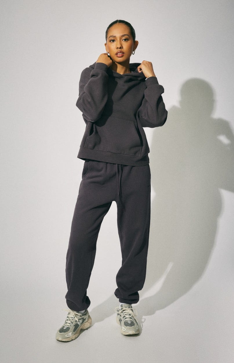 Model wears a dark grey hoodie and matching sweatpants.